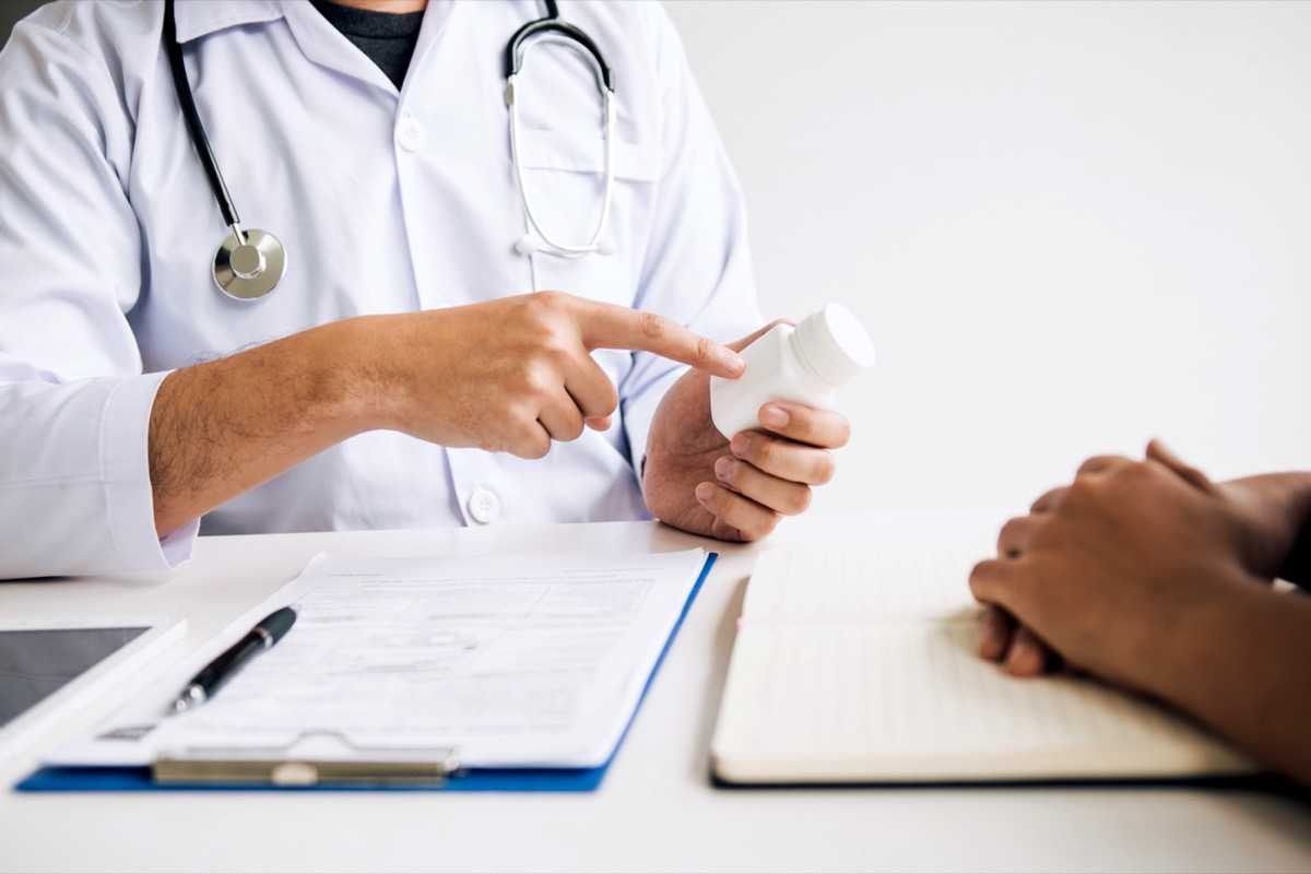 doctor pointing at pill bottle counseling patient