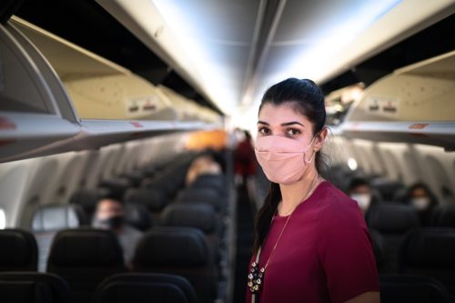 Portrait of young traveller woman wearing face mask on airplane