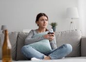 Sad frustrated tired caucasian pretty millennial woman with glass of wine suffering from depression, loneliness and stress at home, empty space. Bad relationships, problems, addiction and crisis