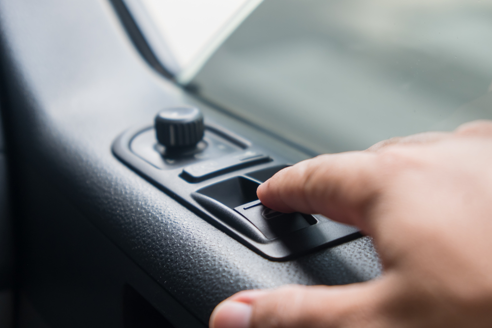 A close of up a hand pressing a button to open or close a car window