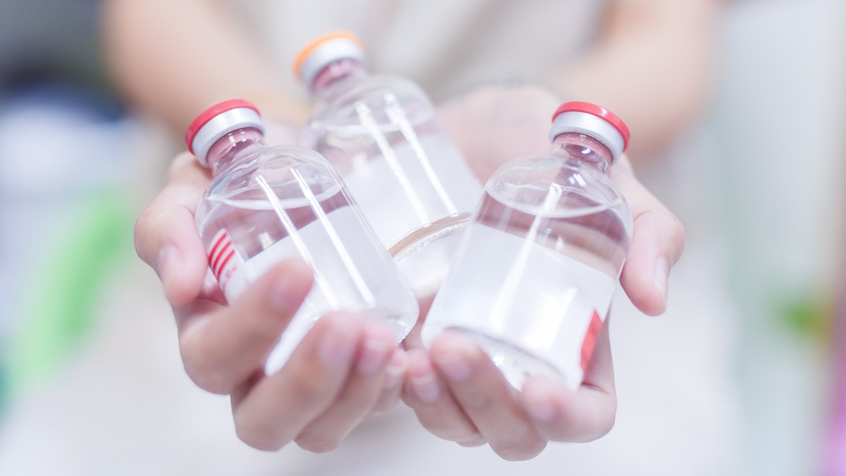 hands holding three glass vials of medicine