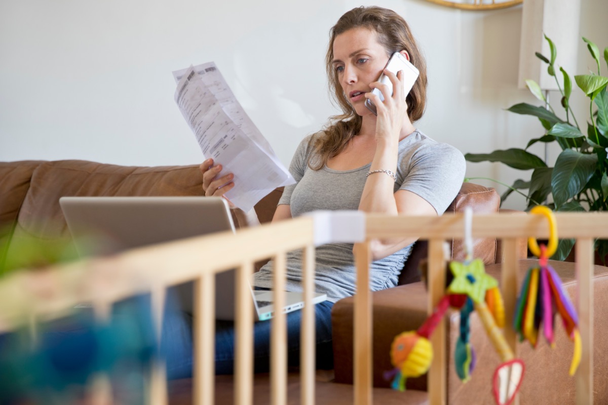 woman taking phone call while reading bills