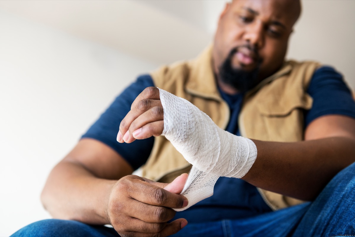 man bandaging hand while injured