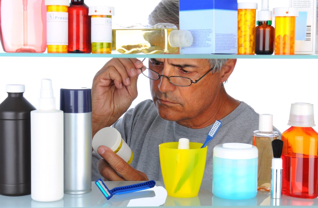 Man reading a prescription label in front of his bathroom Medicine Cabinet