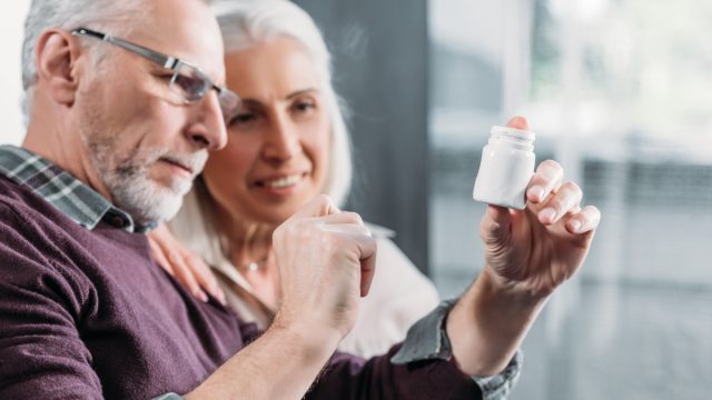 older man and woman looking at pill bottle