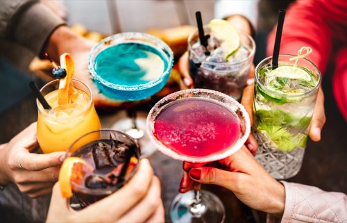 Hands toasting with multi-colored drinks