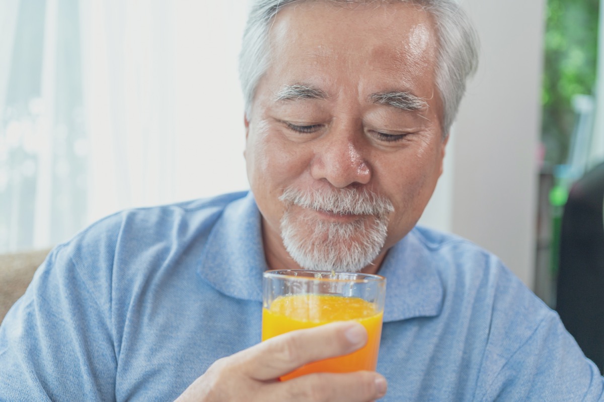 older man drinking glass of orange juice