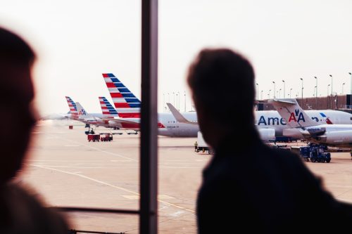 Chicago, IL, USA - July 17, 2017: American Airlines fleet of airplanes at O'Hare Airport viewed from inside the airport terminal with passengers.