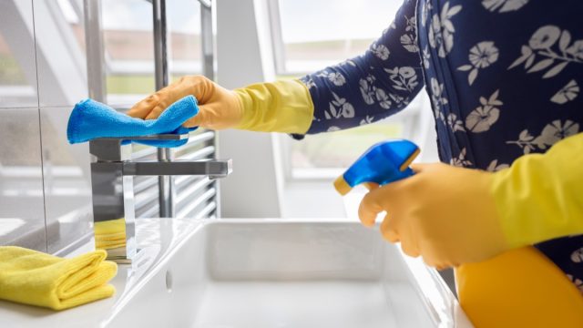 person wearing gloves cleaning bathroom sink