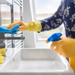 person wearing gloves cleaning bathroom sink