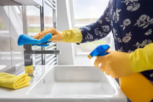 person wearing gloves cleaning bathroom sink