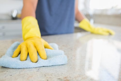 person wearing gloves cleaning kitchen counter