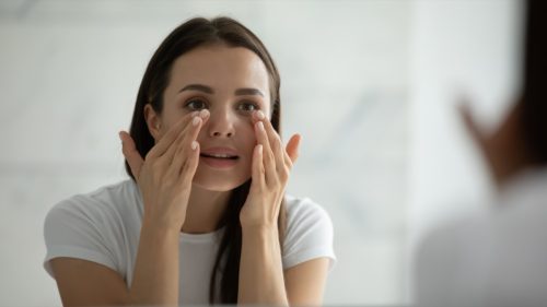 Woman looking at her eyes in the mirror