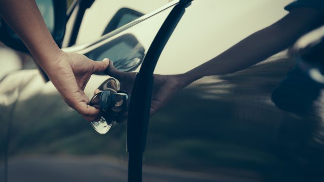 A close up of a person opening a car door