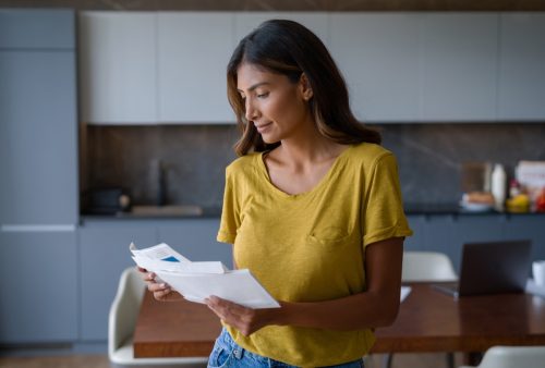 woman at home checking mail and holding a pile of envelopes - lifestyle concepts