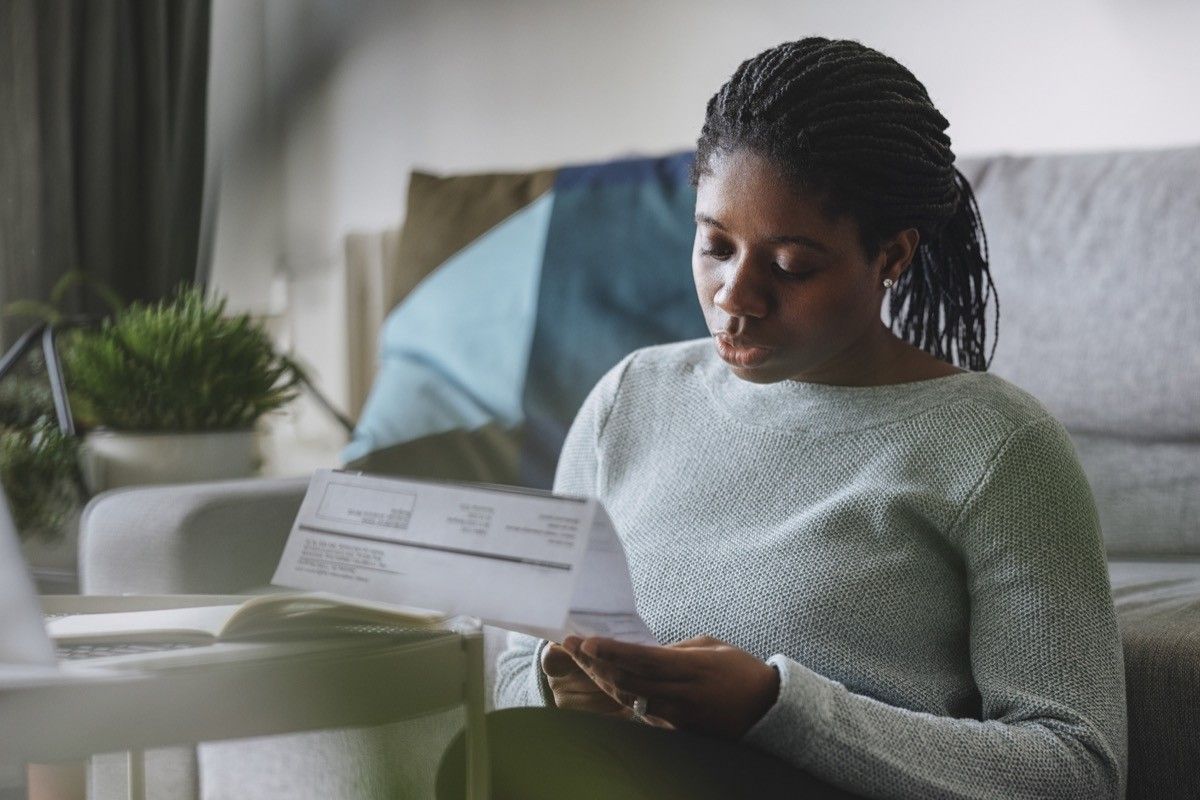 businesswoman reading a utility bill while working remotely from home.