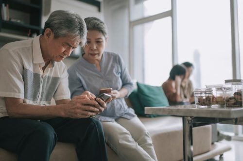 senior couple using smart phone at living room during weekend leisure time