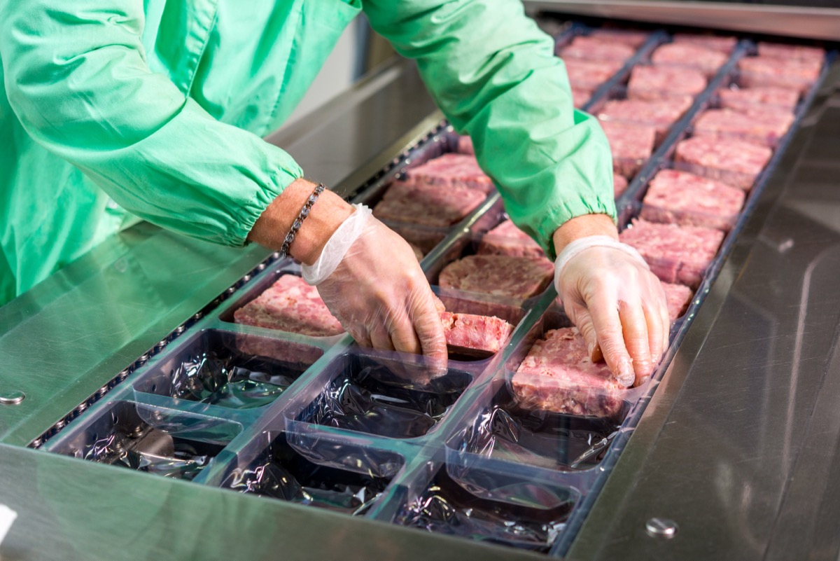 person in factory putting meat into trays