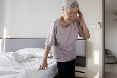 A senior woman standing up from bed and feeling dizzy