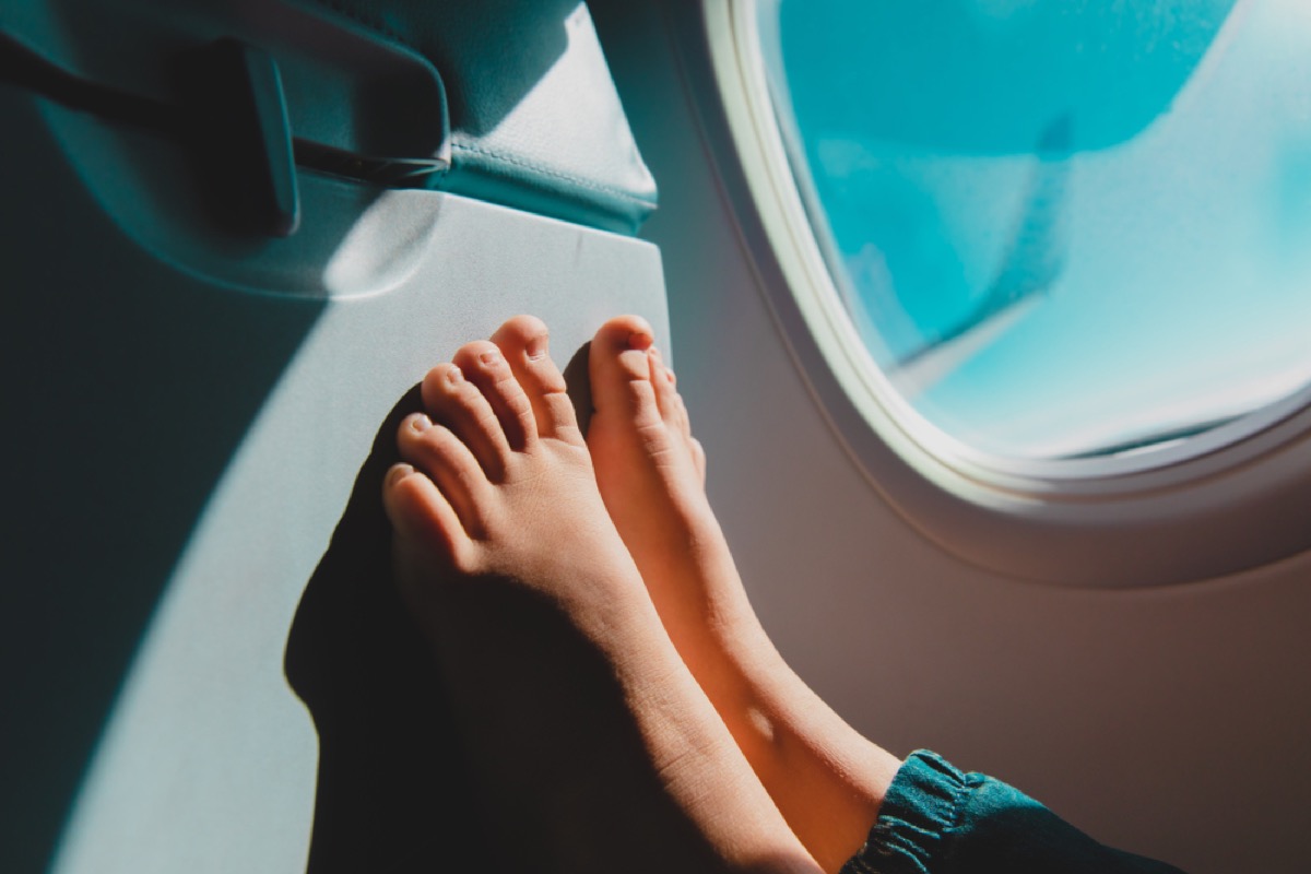 bare feet against a plane window