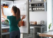 young woman opening fridge door