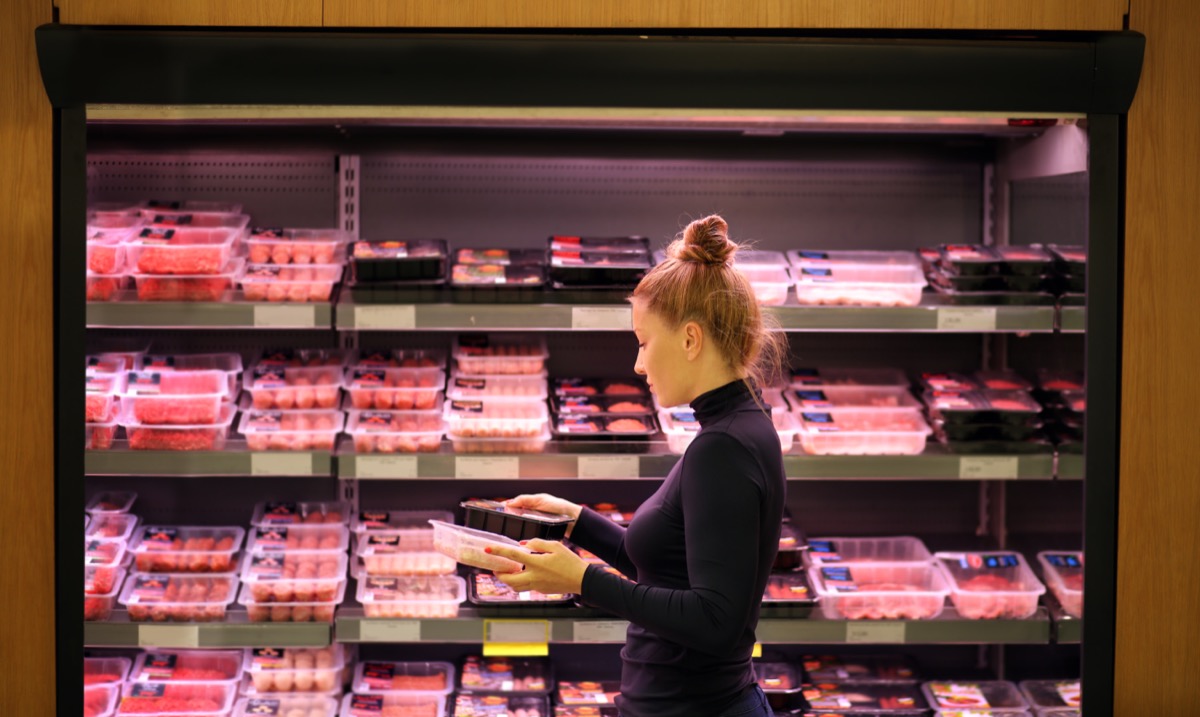 woman in black turtleneck buying meat