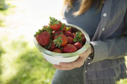 Woman carrying a bowl of strawberries