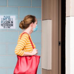 A young woman entering a public restroom bathroom