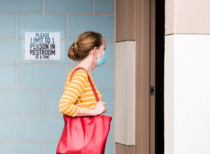 A young woman entering a public restroom bathroom
