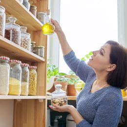 woman reaching for oil in pantry