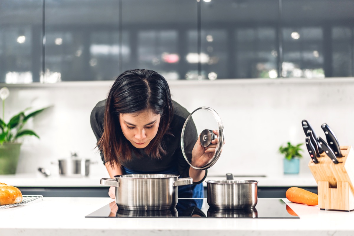 woman smelling a pot of soup on the stove