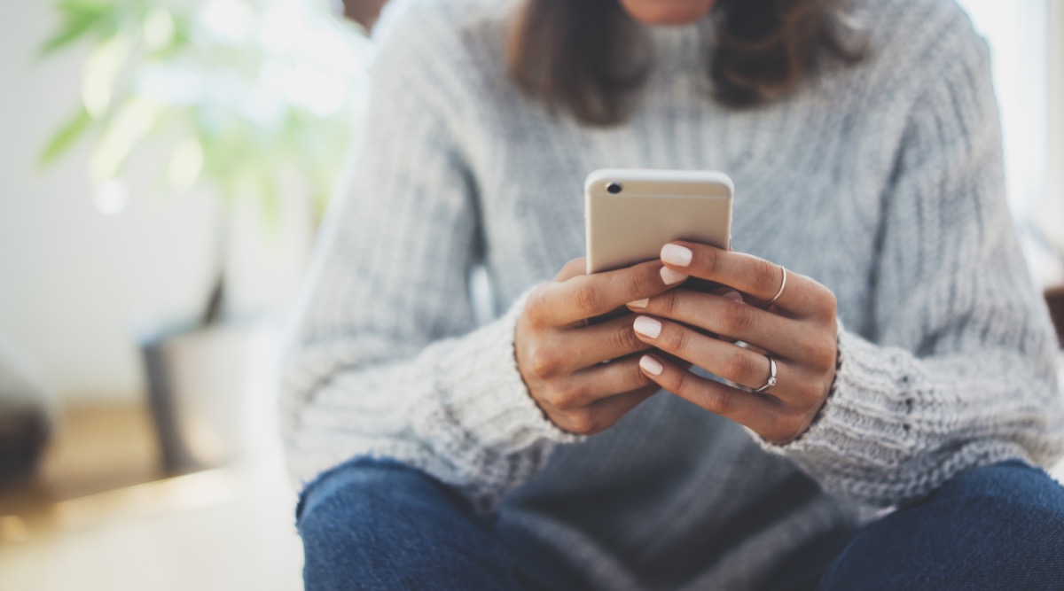 Jeune femme en col roulé textos sur smartphone