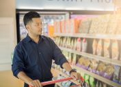 young man in black shirt grocery shopping in snack aisle