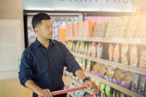 young man in black shirt grocery shopping in snack aisle