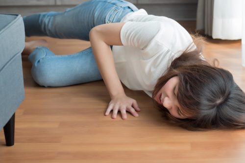 young woman in jeans and a white t-shirt falling on the floor of her home