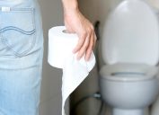 Man holding toilet paper in bathroom