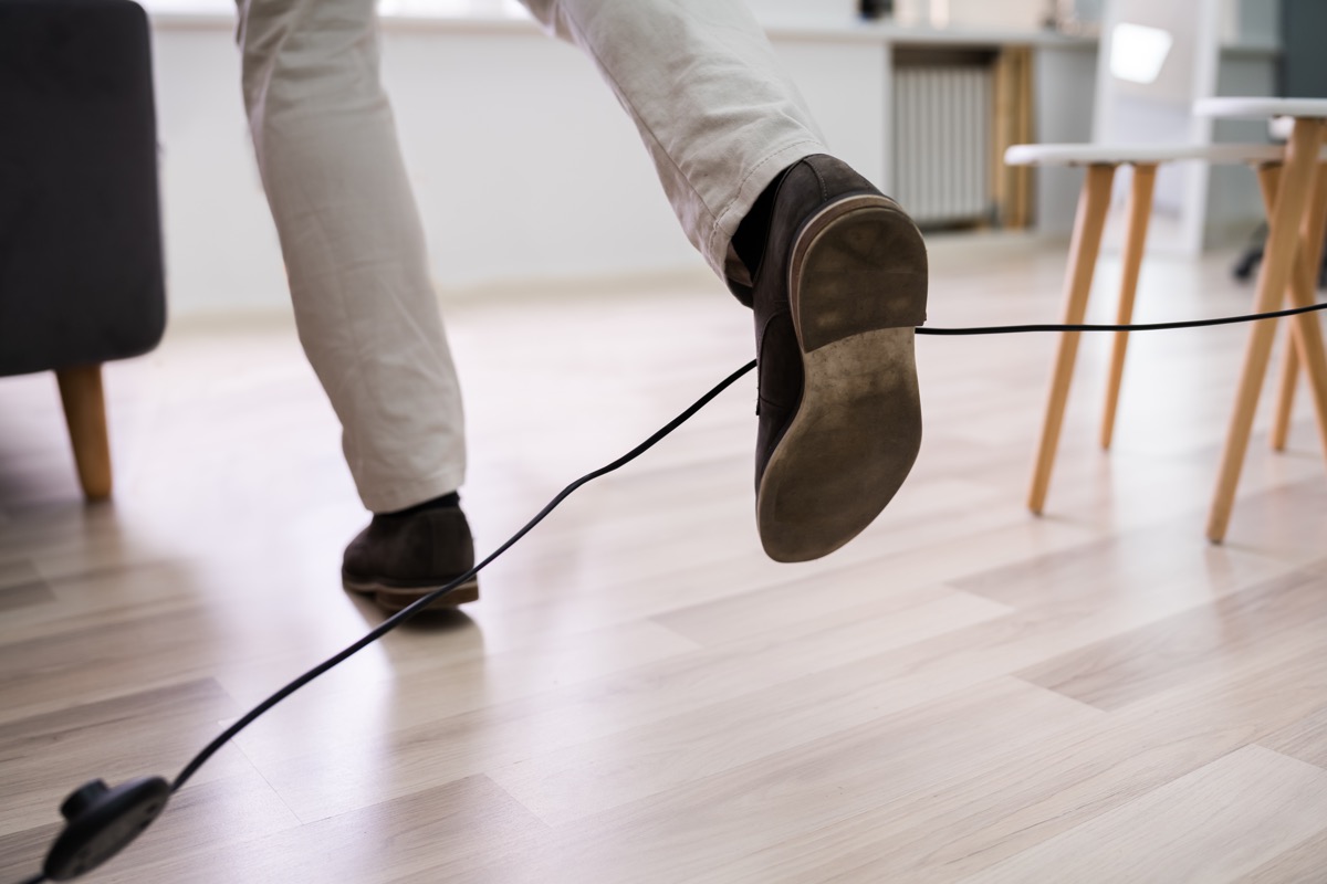 Closeup of man's legs tripping on electrical cord