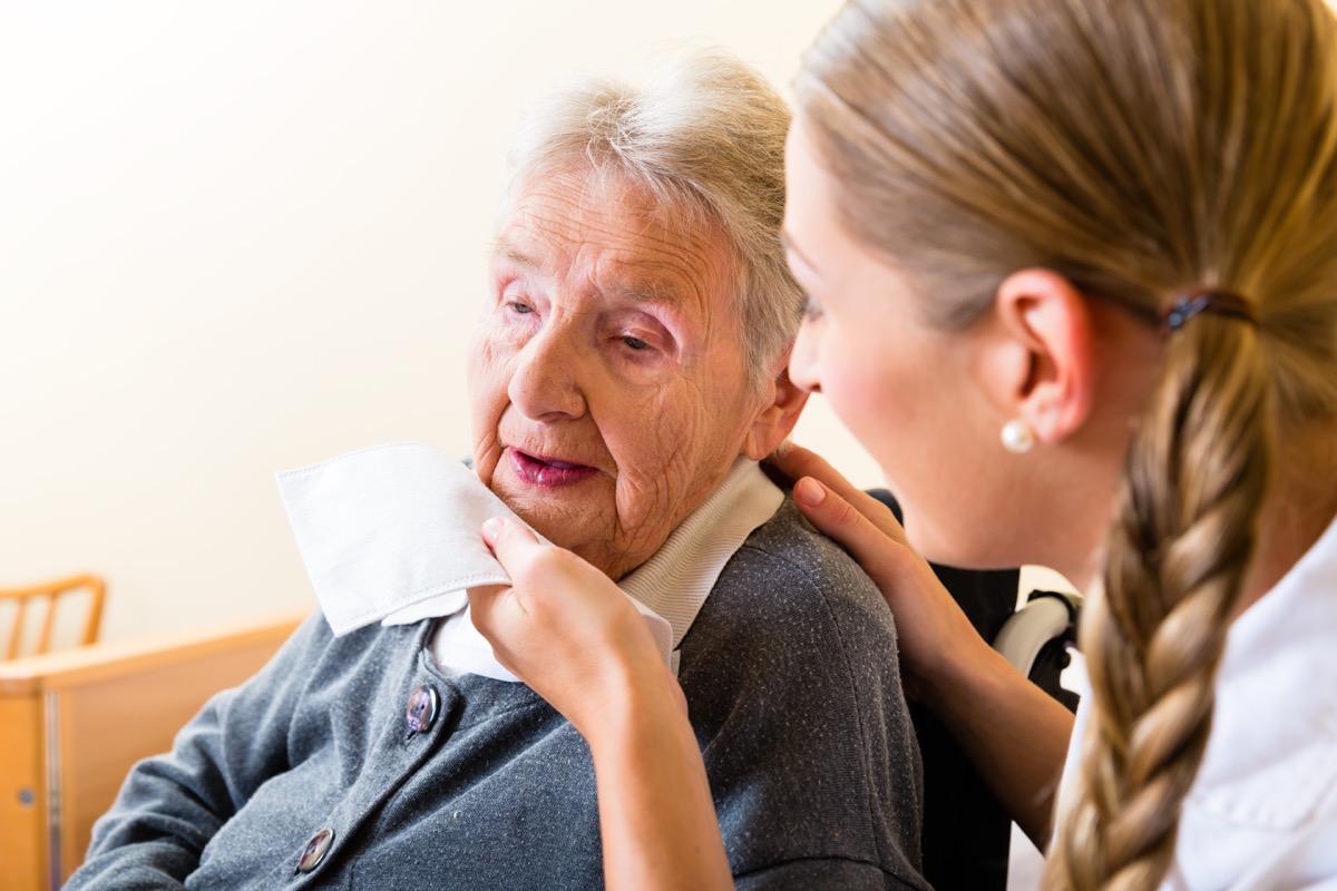 Nurse wiping elderly woman's mouth