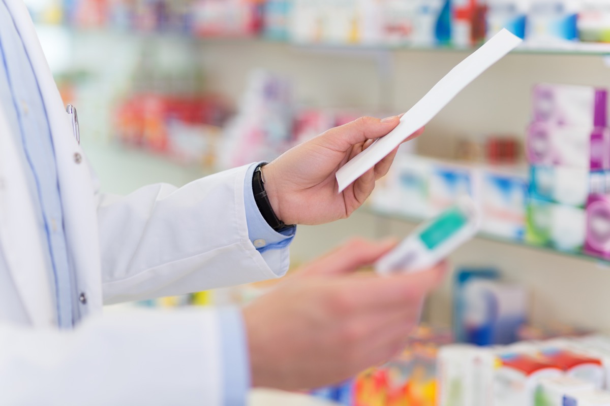 Close-up of pharmacist's hand filling prescription in drugstore