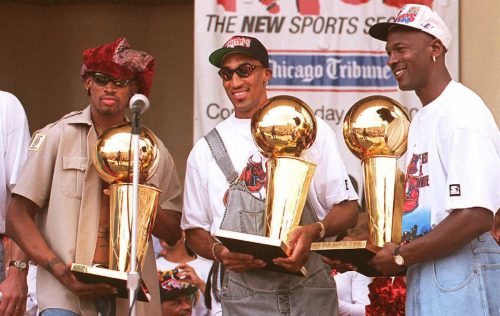 Dennis Rodman, Scottie Pippen, and Michael Jordan holding championship trophies at a rally in Chicago in June 1996