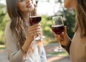 Cropped image of two young women drinking red wine outdoors