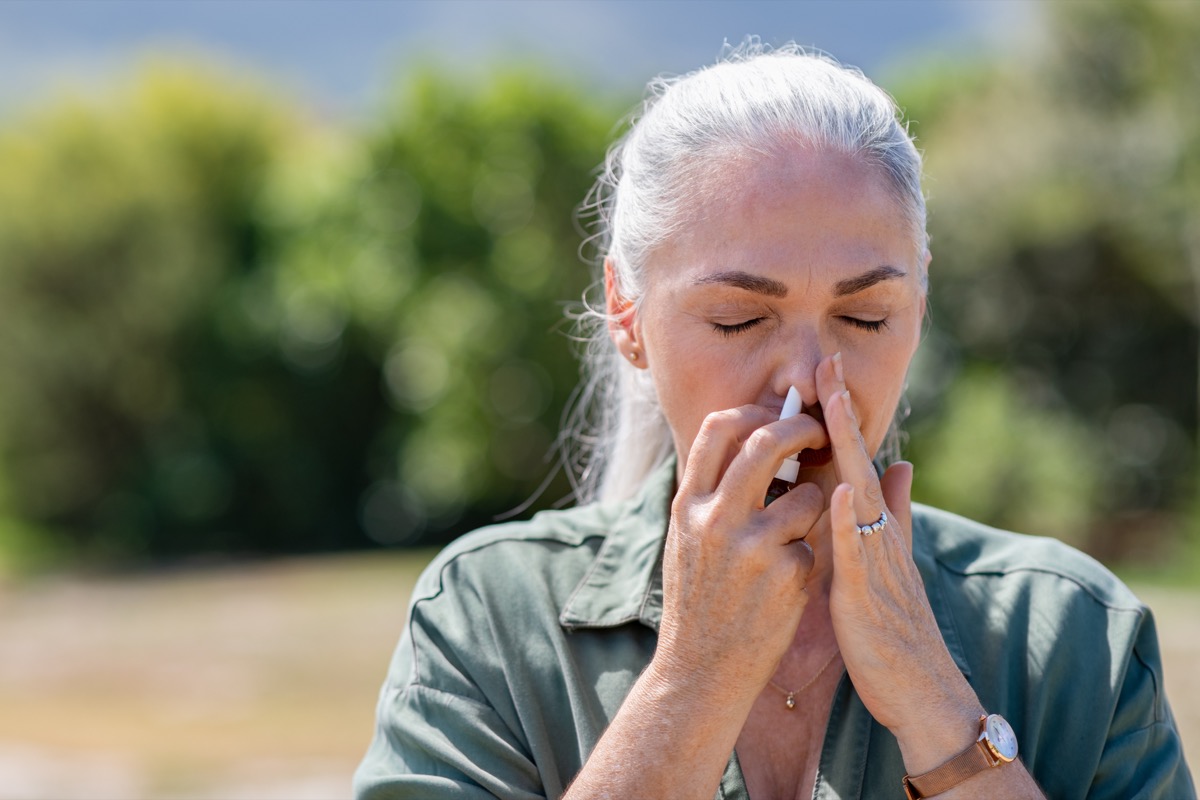 Attractive senior woman using nasal inhaler