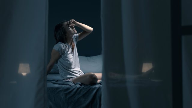 Tired,Woman,Sitting,In,Bed,At,Night,With,Open,Window,