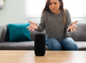 Annoyed woman in her 20s with an angry expression because her smart speaker has an error and is not working