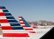 the tail wing of american airlines planes shown lined up at the airport
