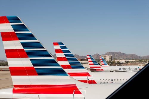 the tail wing of american airlines planes shown lined up at the airport