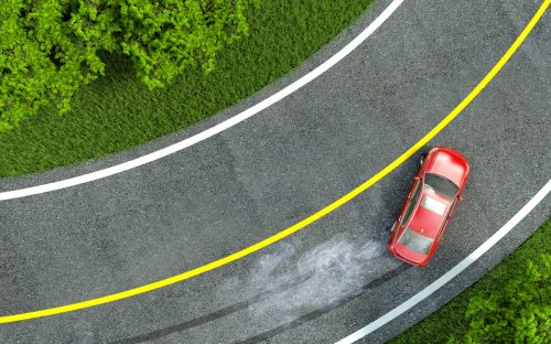 Red car turning and skidding on road