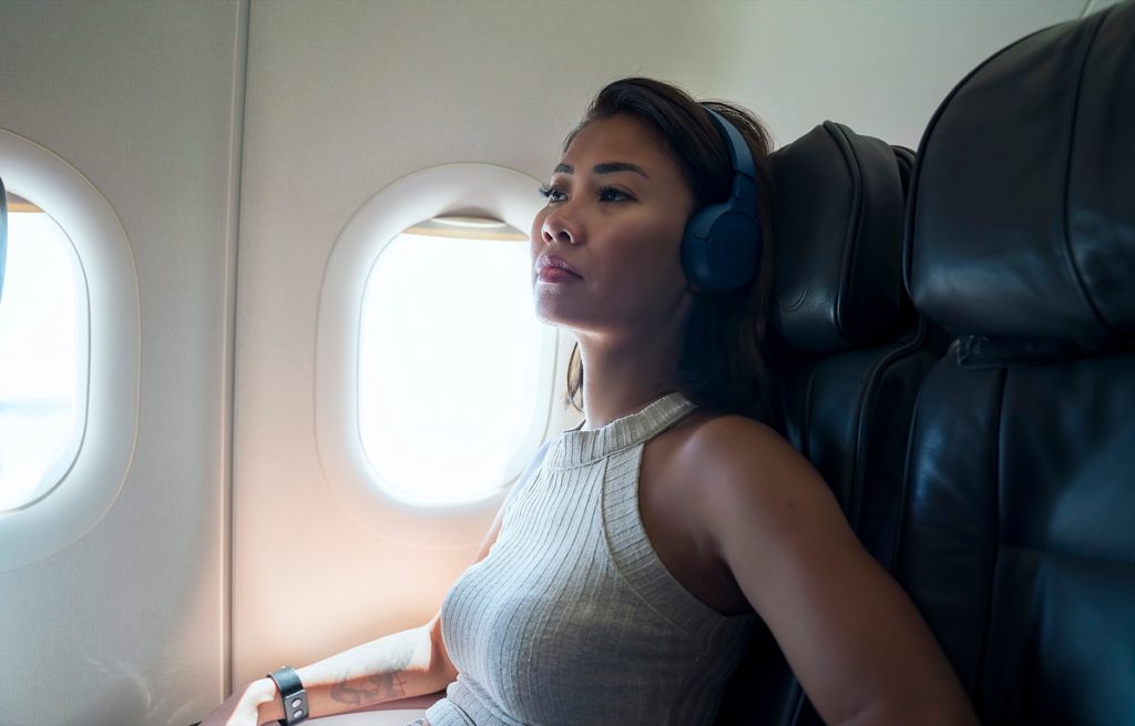 Woman wearing headphones sitting in window airplane seat