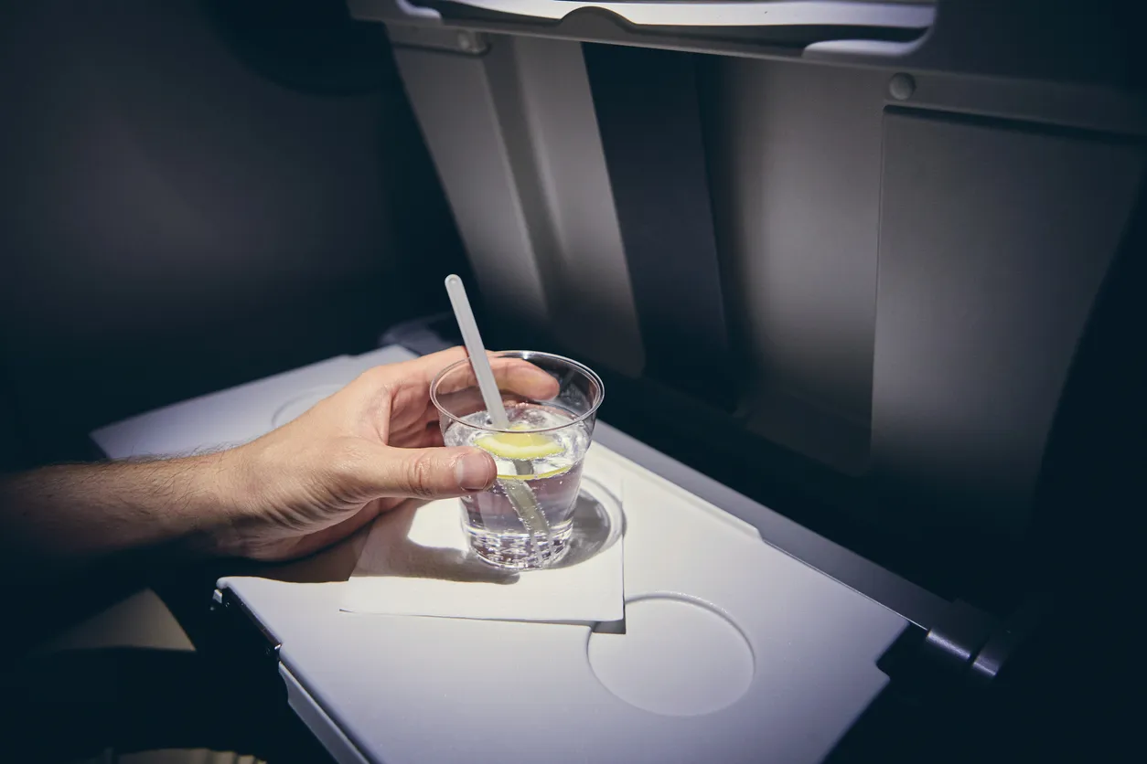 A close up of a person drinking a cocktail on a plane