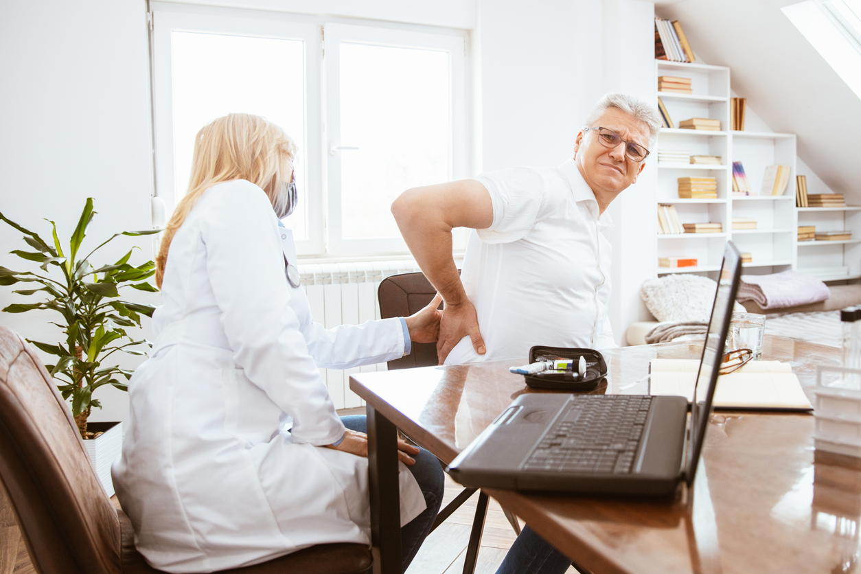 A doctor examining a man's kidneys in her office